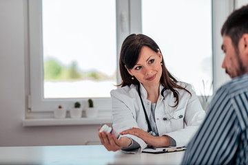 Doctor holding a pill bottle while talking with a patient in the office.