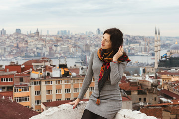 Romantic young woman enjoys a picturesque panoramic view of Istanbul from the roof. Tourist girl on the background of autumn Istanbul.