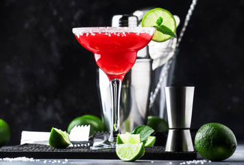 Watermelon margarita, alcoholic cocktail with silver tequila, lime juice, mint, watermelon and crushed ice, metal bar tools, gray background