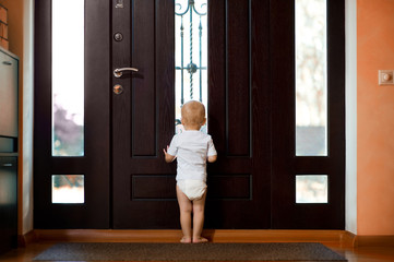 little girl waiting near the front door of mom and dad. Back view