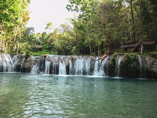 woman swinging with the rope at the pool of waterfalls, Cambugahay Falls on Siquijor Island in Philippines