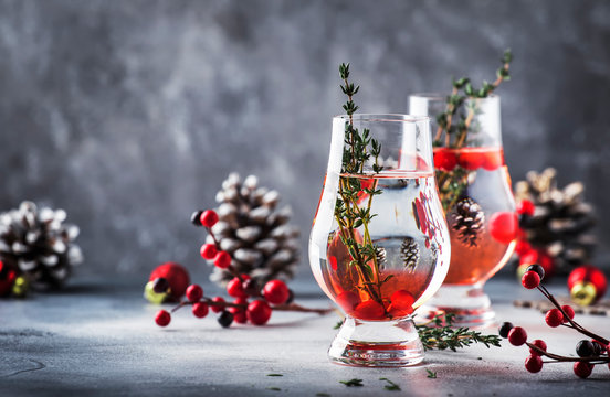 Winter alcoholic cocktail with red berries, liquor, gin, thyme and vodka for Christmas or New Year. Holiday table setting