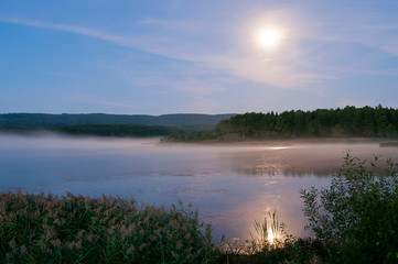 colorful moon on autumn lake at dawn with forest