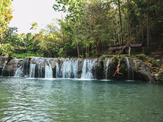 woman swinging with the rope at the pool of waterfalls, Cambugahay Falls on Siquijor Island in Philippines