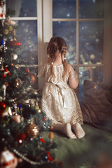 A child looks out the frozen window on Christmas night waiting for magic. Postcard concept, book cover.