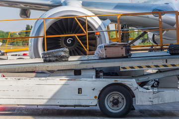 Travel bags and airplane in airport. Loading suitcases on an aircraft, preparing for flight