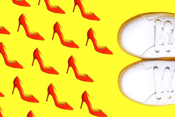 White sneakers against female red shoes on yellow.