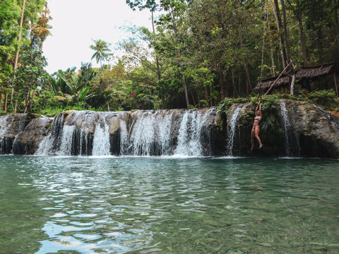 woman swimming alone at the tropical wild nature of waterfalls, cambugahay falls in Siquijor Island in Philippines