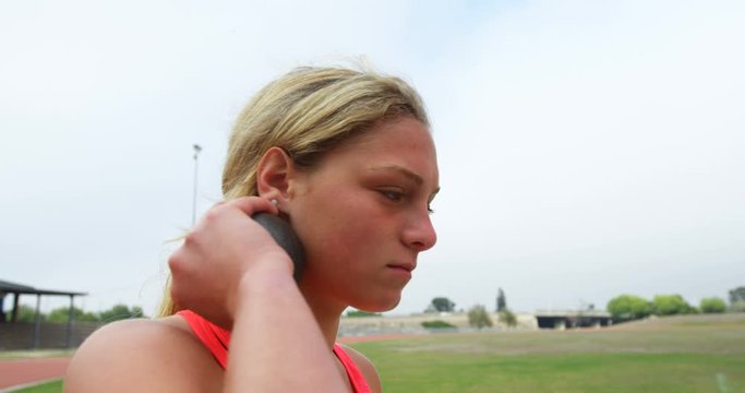 Side view of Caucasian female athlete getting ready for throw shot put throw at sports venue 4k