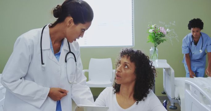 Front view of African american female doctor discussing medical report with disabled female patient