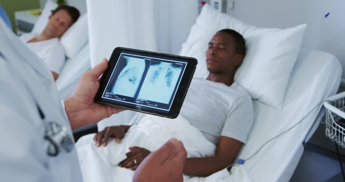 Close-up of Caucasian male doctor looking at x-ray report on digital tablet in the ward