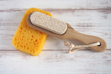 Yellow spongewashcloth with pumice. Self-care items on a wooden background, zero waste concept. Copy space