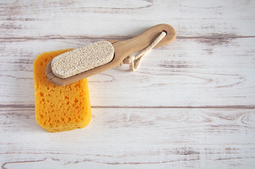 Yellow spongewashcloth with pumice. Self-care items on a wooden background, zero waste concept....