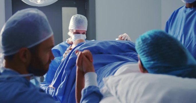Caucasian female surgeon examining pregnant woman during labor in operation theater at hospital