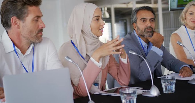 A panel of mixed-race business delegates talking at a conference