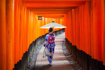 Woman in traditional kimono and umbrela walking at torii gates, Japan - obrazy, fototapety, plakaty
