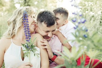 a mother with a son tickle a father's ears