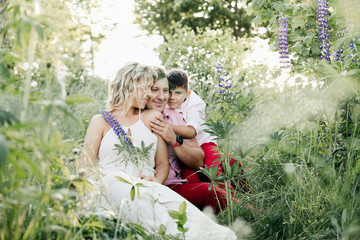 a mother with a son hug a father among greenery lawn