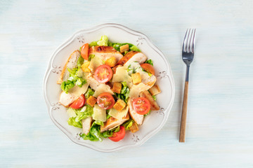 Chicken Caesar salad, shot from above on a light blue background
