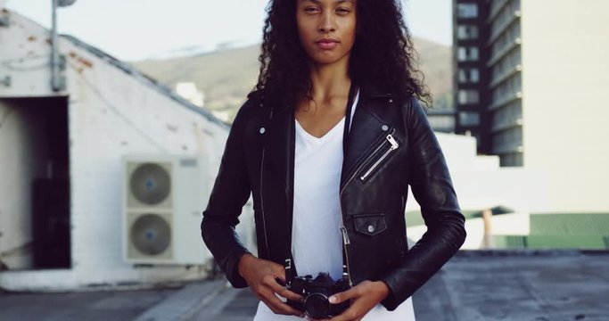 Fashionable young woman on urban rooftop holding a camera