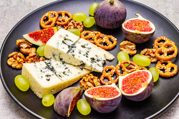 Cheese plate with blue cheese, walnuts, figs, grapes, pretzels