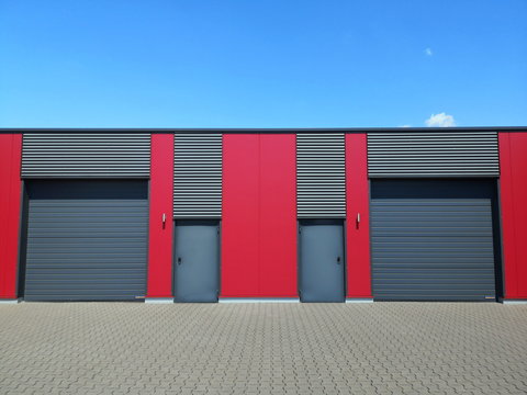 Moderne Architektur eines Gewerbebau in Rot und Grau mit modernem Sektionaltor vor blauem Himmel im Sonnenschein am Oldtimer-Park Lippe in Lage bei Detmold im Lipperland in Ostwestfalen-Lippe