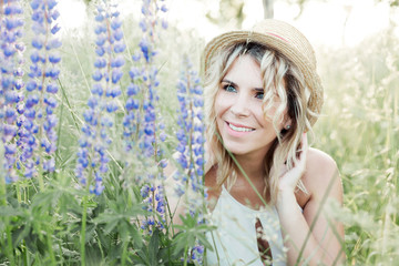 a beautiful young woman looks at lupines