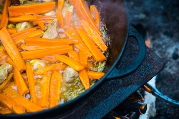 Roasted carrots with onions and meat in a cauldron. The process of cooking pilaf on the fire....
