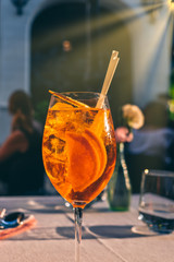 Glass of Aperol Spritz cocktail on the table in street restaurant, famous refreshing drink in sunny day