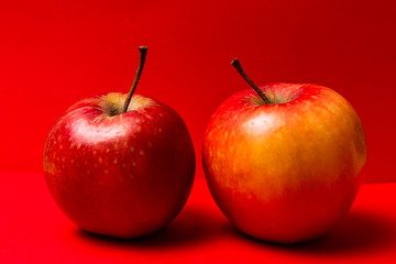 Two red apples on a red background.