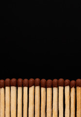 A row of matches on a black background. Vertical photo. Place for text