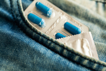 Medical potency pills and condom on jeans.