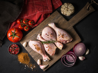 Raw chicken on a wooden board on a black background