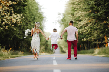 parents walking on a road and toss their son holding by hands him