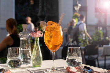 Glass of Aperol Spritz cocktail on the table in street restaurant, famous refreshing drink in sunny day
