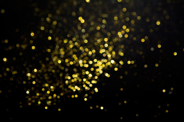 Abstract blurred festive glitter bokeh background in gold, on black
