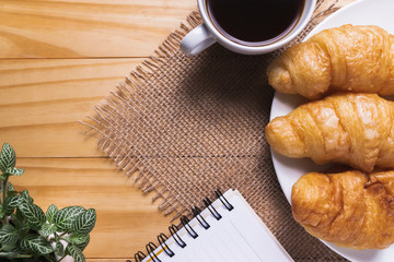 Closeup croissant with coffee on wooden table. breakfast concept.