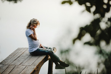 a woman crossed her feet and sits on a bridge