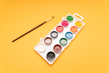watercolor paints in box on yellow background