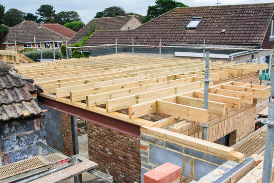 Renovation projects. Building of extension of the existing house, unfinished wooden roof structure, brick walls, view from scaffoliding, selective focus