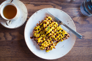 gluten-free veggie waffles with lemon cream. Flat lay dish, wooden table, cup of herbal tea