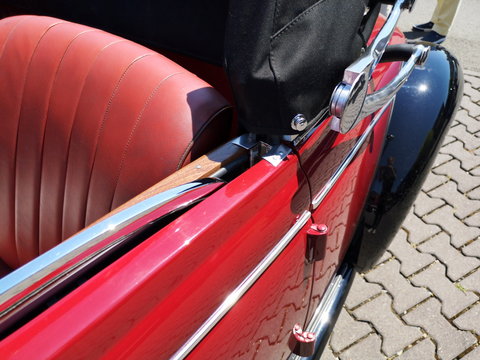 Deutsches Luxus Cabriolet ins Rot und Schwarz der Vierzigerjahre und Nachkriegszeit im Sommer bei Sonnenschein beim Oldtimertreffen im Oldtimer-Park Lippe in Lage bei Detmold in Ostwestfalen-Lippe - Powered by Adobe