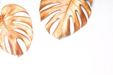 Two decorative golden painted leaves of monstera plant on white