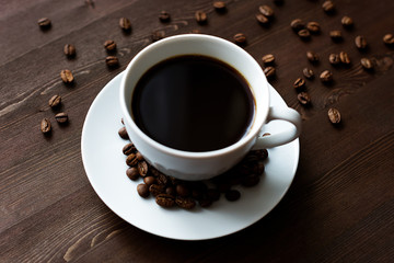 cup of coffee with beans on wooden background