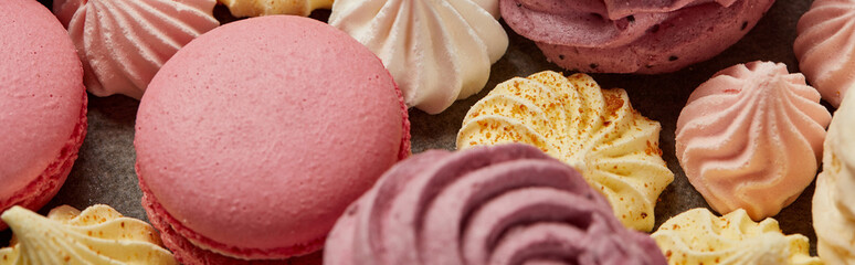 Gourmet sweet pink macaroons, assorted small meringues and zephyr on gray background