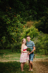 Fototapeta premium In waiting baby. happy family. pregnant woman with beloved husband embrace, barefoot on the grass. round belly. The sincere tender moment. background, nature, park, tree, forest, nine month. happiness