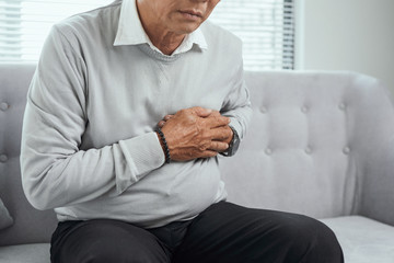 Old man feel pain in their heart  in living room, medical concept