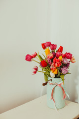 Multicolor tulips in metal vase on white background