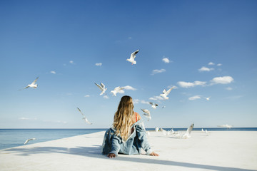 a girl sits on berth and watch at seagulls