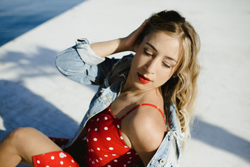 a girl in red polka dots dress and jeans jacket poses for a photo